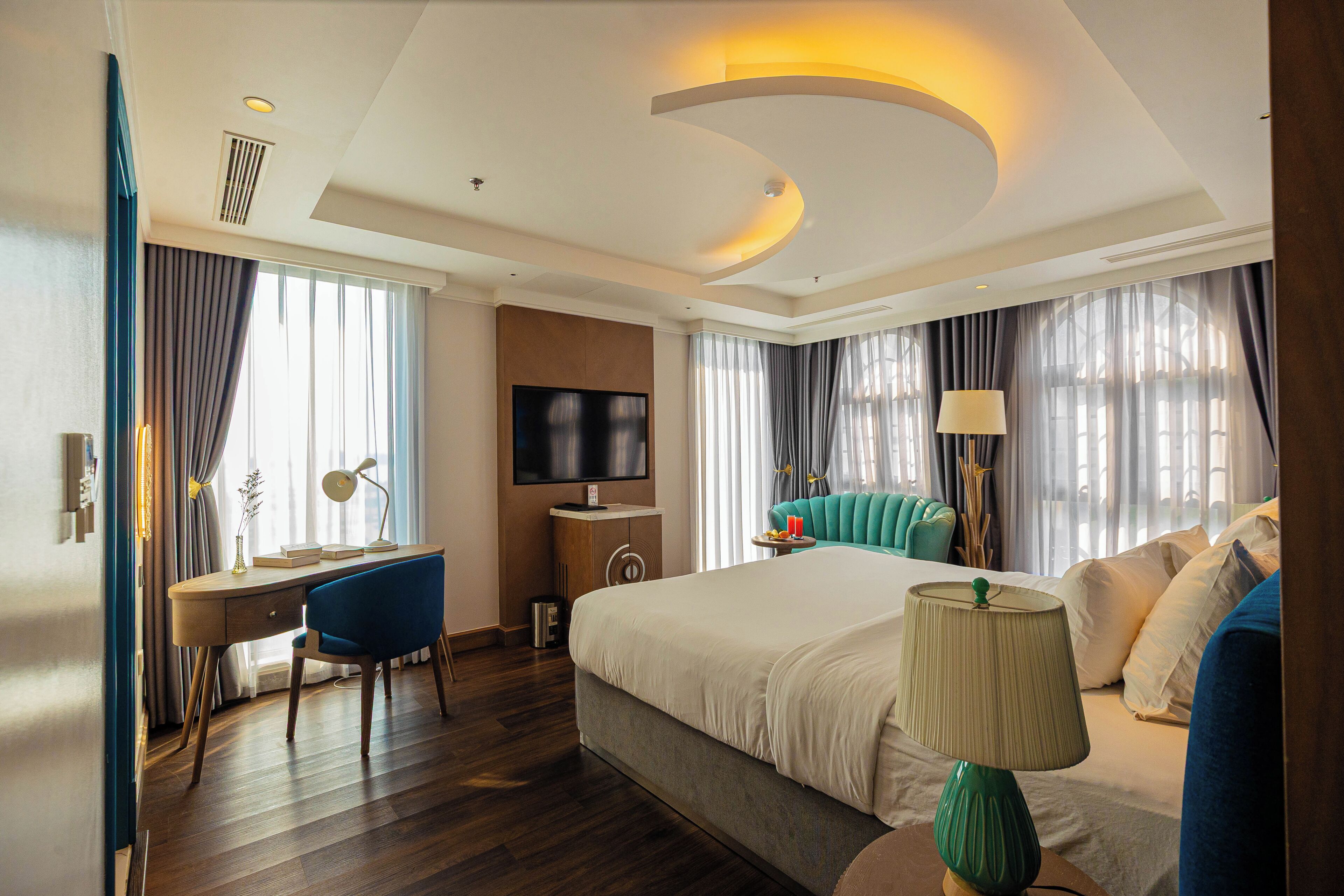 Una habitación de hotel con cama, escritorio, silla, televisor y lámpara.