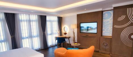 A hotel room with a bed, a desk with a chair, a television, and a decorative wall panel.