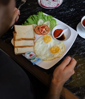 A plate with toast, eggs, tomatoes, lettuce, and a small bowl of sauce. - The Moon Boutique Hotel Cat Ba (Hai Phong)