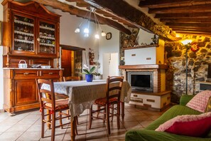 Una cocina rústica con armarios de madera, una mesa de comedor, sillas y una pared de piedra.