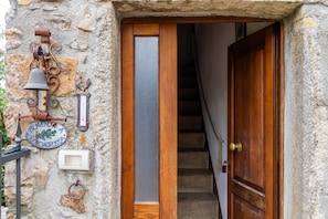 Un muro de piedra con una puerta de madera, una campana y un letrero.