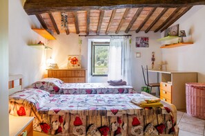Un dormitorio con dos camas, techo de madera, ventana con cortinas, un escritorio y una silla.