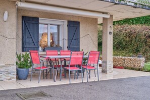 Un espace extérieur abrité, avec une table et des chaises, une plante en pot et un mur en pierre.