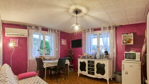 Ein Zimmer mit einem Bett, einem Schreibtisch, einem Stuhl, einem Fernseher, einer Mikrowelle und einem Kühlschrank.