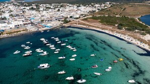 Vue aérienne d’une ville côtière, avec des bateaux amarrés le long de la côte et une plage.