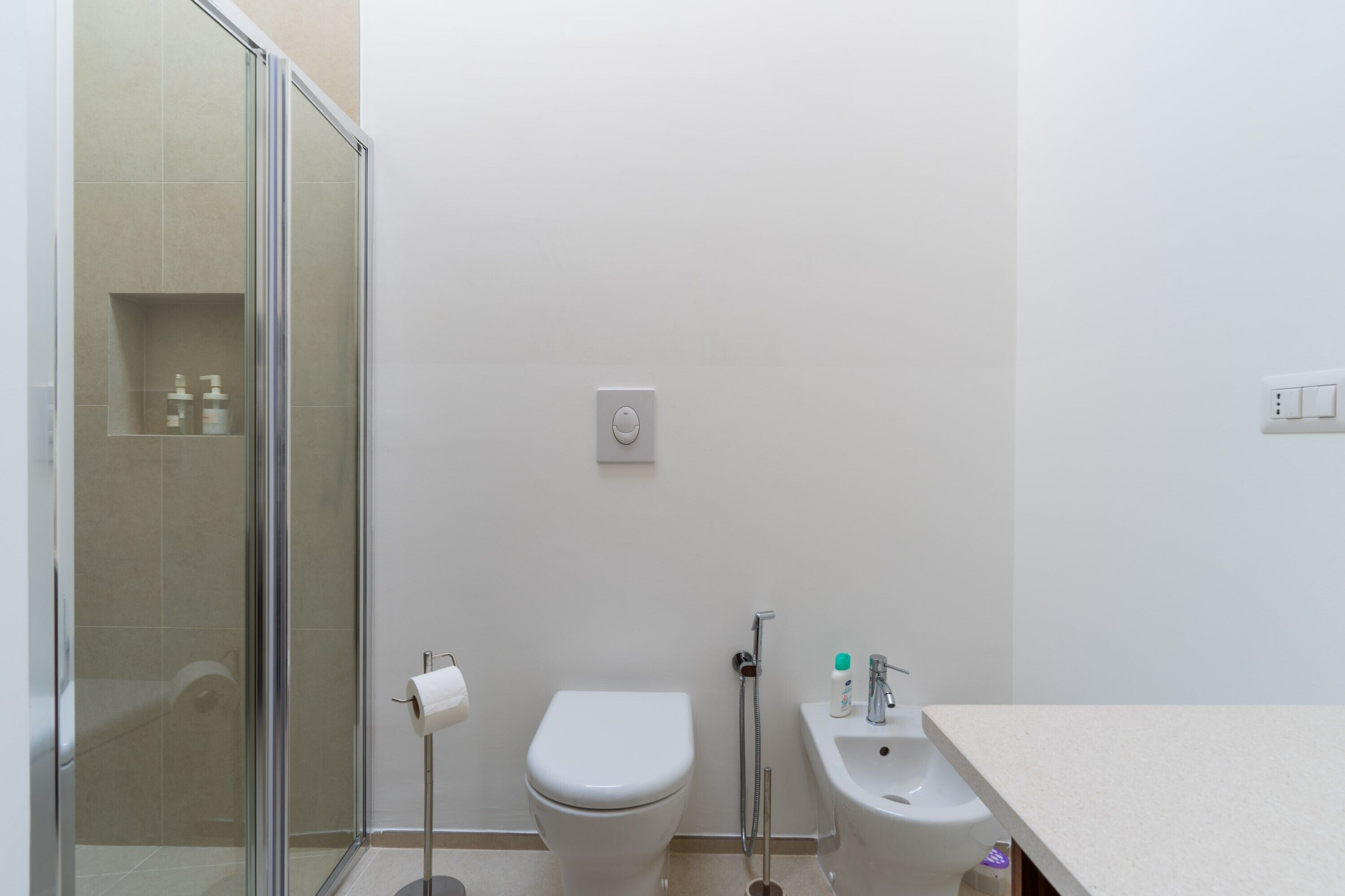 A bathroom with a toilet, bidet, and glass shower enclosure.