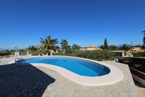 A swimming pool with a stone deck, surrounded by palm trees and a clear blue sky. - Villa 'Khiter' with Private Pool, Wi-Fi and Air Conditioning (Dénia)