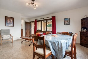 A dining area with a round table, chairs, a chandelier, and artwork on the walls. - Villa 'Khiter' with Private Pool, Wi-Fi and Air Conditioning (Dénia)
