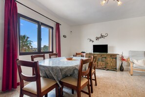 A dining area with a round table, wooden chairs, a TV, and a sofa. - Villa 'Khiter' with Private Pool, Wi-Fi and Air Conditioning (Dénia)