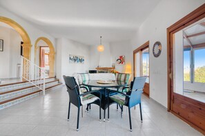 A dining area with a round table and chairs, a staircase with patterned steps, and a view through a glass door.