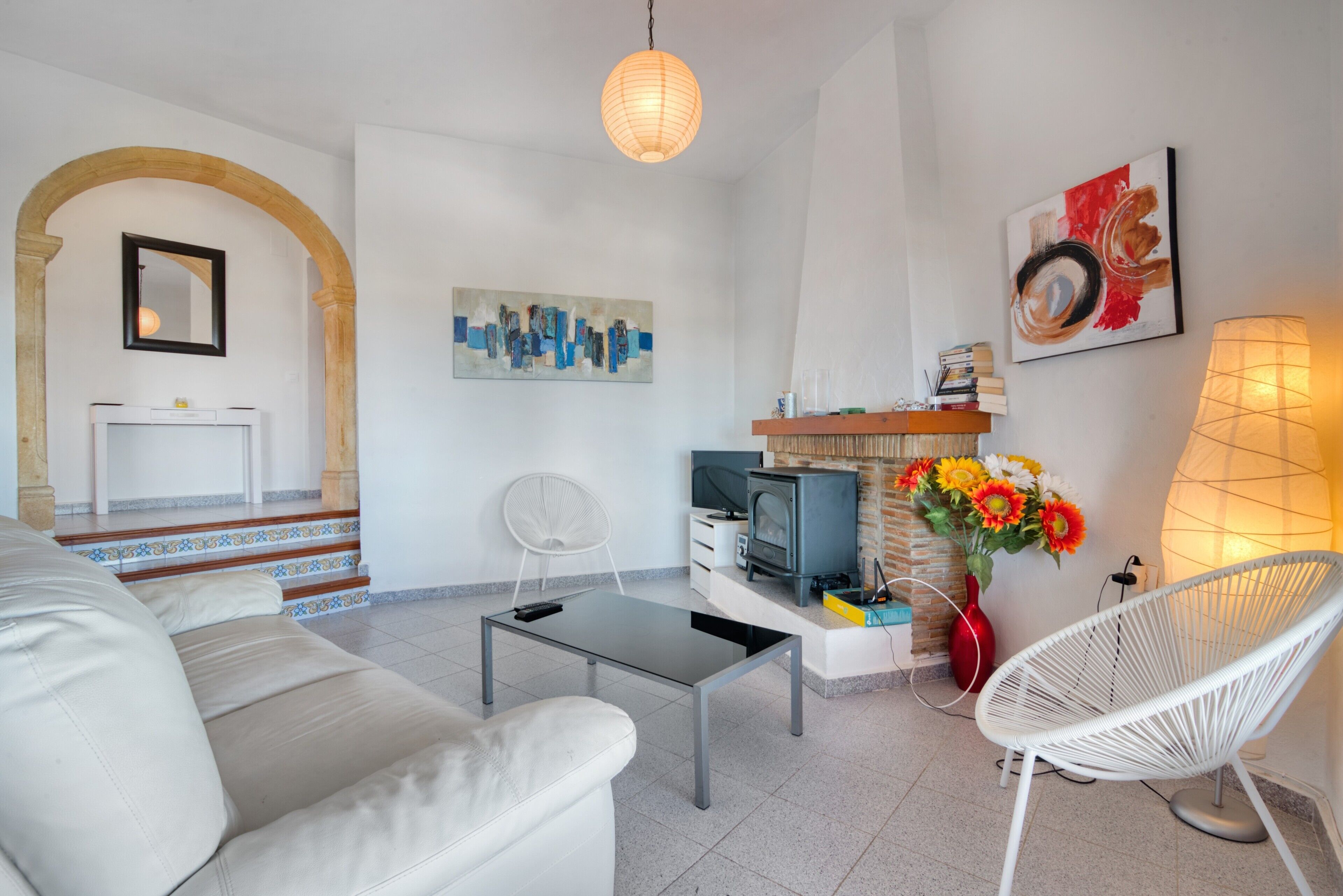 Een woonkamer met een bank, een salontafel, een televisie, een open haard, een fauteuil en kunstwerken aan de muur.