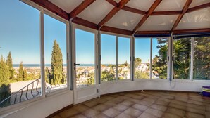 A room with large windows, a tiled floor, and a view of the sea and trees. - Villa 'Alta' with Private Pool, Wi-Fi and Air Conditioning (Dénia)