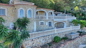 Un edificio in pietra con balconi, un muro di pietra e un giardino.