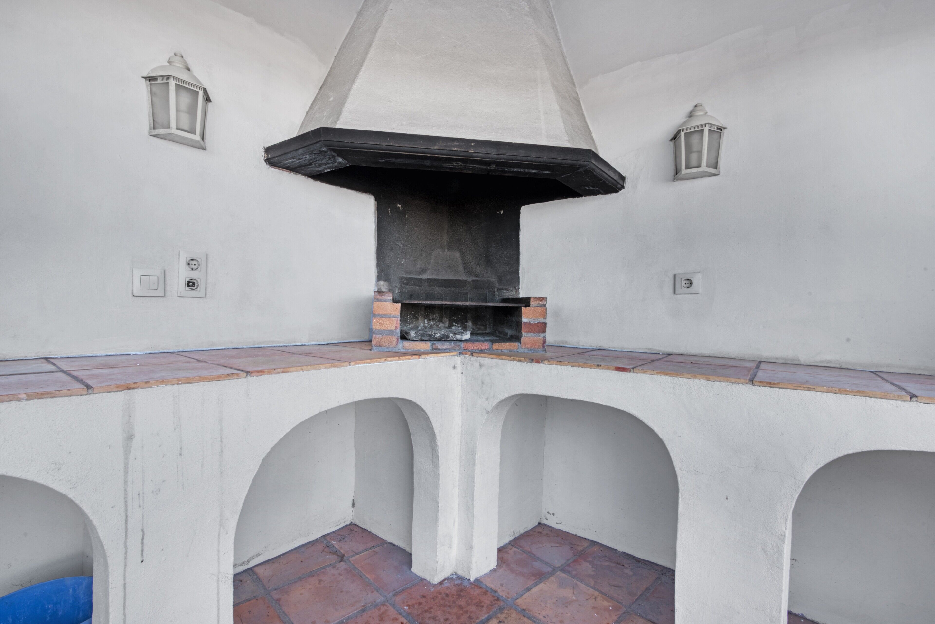 A corner with a brick fireplace, white walls, and two wall-mounted lanterns.