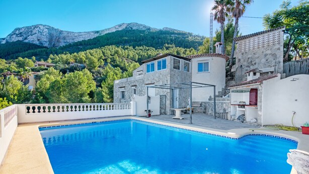 A swimming pool with a mountain backdrop, a stone building, and a white fence. - Villa 'Nicoll' with Private Pool, Wi-Fi and Air Conditioning (Dénia)