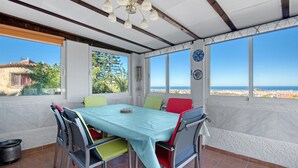 A dining area with a table and chairs, large windows with a view of the sea, and a ceiling with exposed beams. - Villa 'Nicoll' with Private Pool, Wi-Fi and Air Conditioning (Dénia)