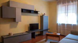 A living room with a flat-screen TV, a sofa, a coffee table, and built-in shelving. - Apartment "Semia" with Mountain View, Balcony & Wi-Fi (Vinadio)