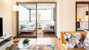 A modern living room with a sofa, a coffee table, and a TV. - Vacation Home "La Tejita Beach House" with Mountain View, Shared Pool & Wi-Fi (La Tejita)