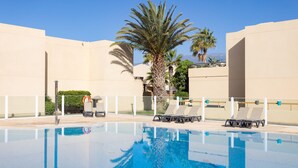 A swimming pool with lounge chairs and palm trees. - Vacation Home "La Tejita Beach House" with Mountain View, Shared Pool & Wi-Fi (La Tejita)