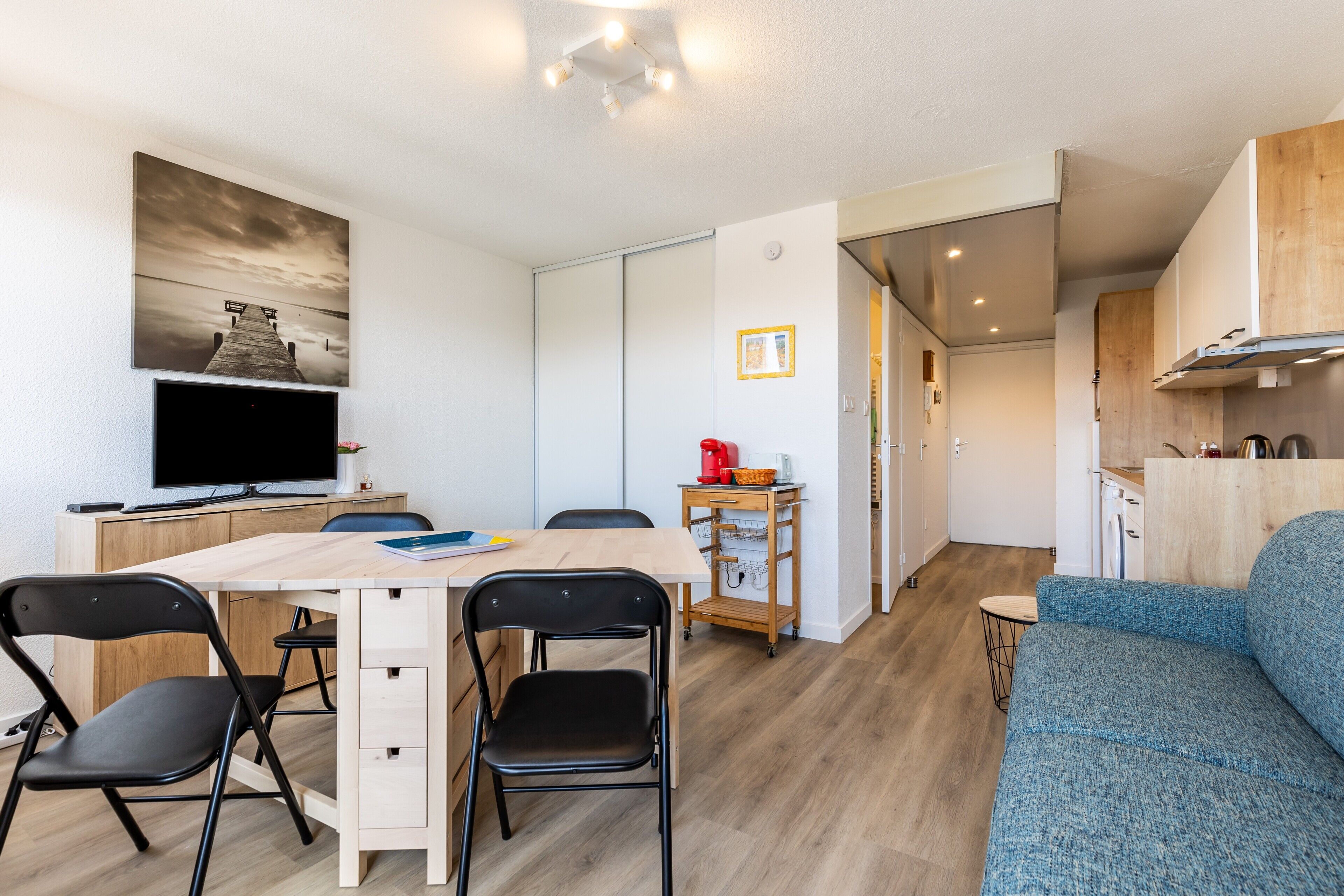 Une cuisine moderne avec des meubles en bois, une cuisinière encastrée et un coin repas comprenant une table et des chaises.