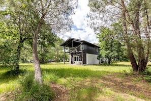 A cabin with a porch, surrounded by trees and grass.
