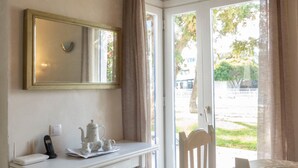 A room with a white desk, a chair, a small table with a teapot, a telephone, and a window with curtains. - Holiday Home 'Los Barqueros 13' with Shared Pool, Private Terrace & Wi-Fi (Corralejo)