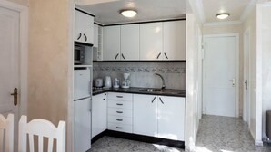 A compact kitchen with white cabinets, a built-in microwave, a coffee maker, and a sink. - Holiday Home 'Los Barqueros 13' with Shared Pool, Private Terrace & Wi-Fi (Corralejo)