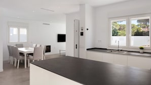 Eine moderne Küche mit dunkler Arbeitsplatte, weißen Schränken und einem Fenster mit Blick auf Grünflächen.