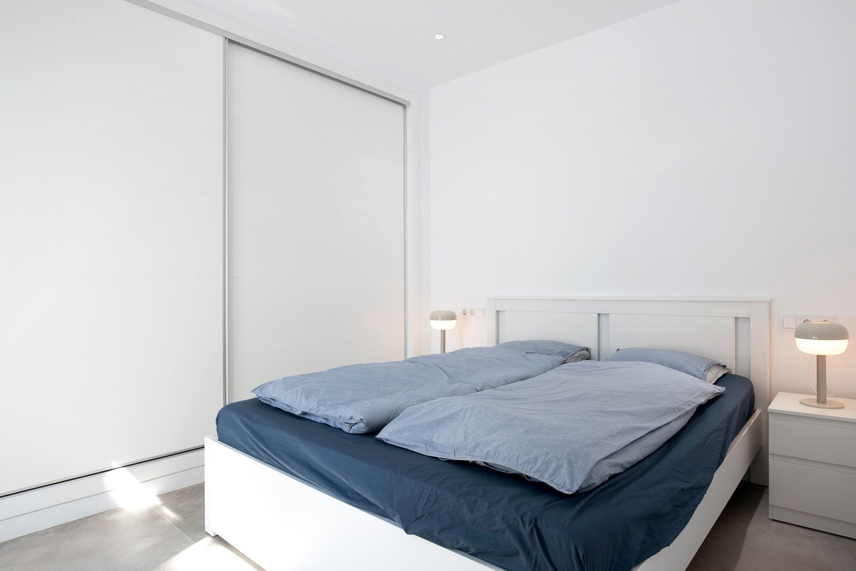 Ein modernes Schlafzimmer mit einem Bett, Nachttischlampen und einer Schiebetür.