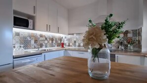 A kitchen with a wooden countertop, a vase with flowers, and patterned backsplash tiles.