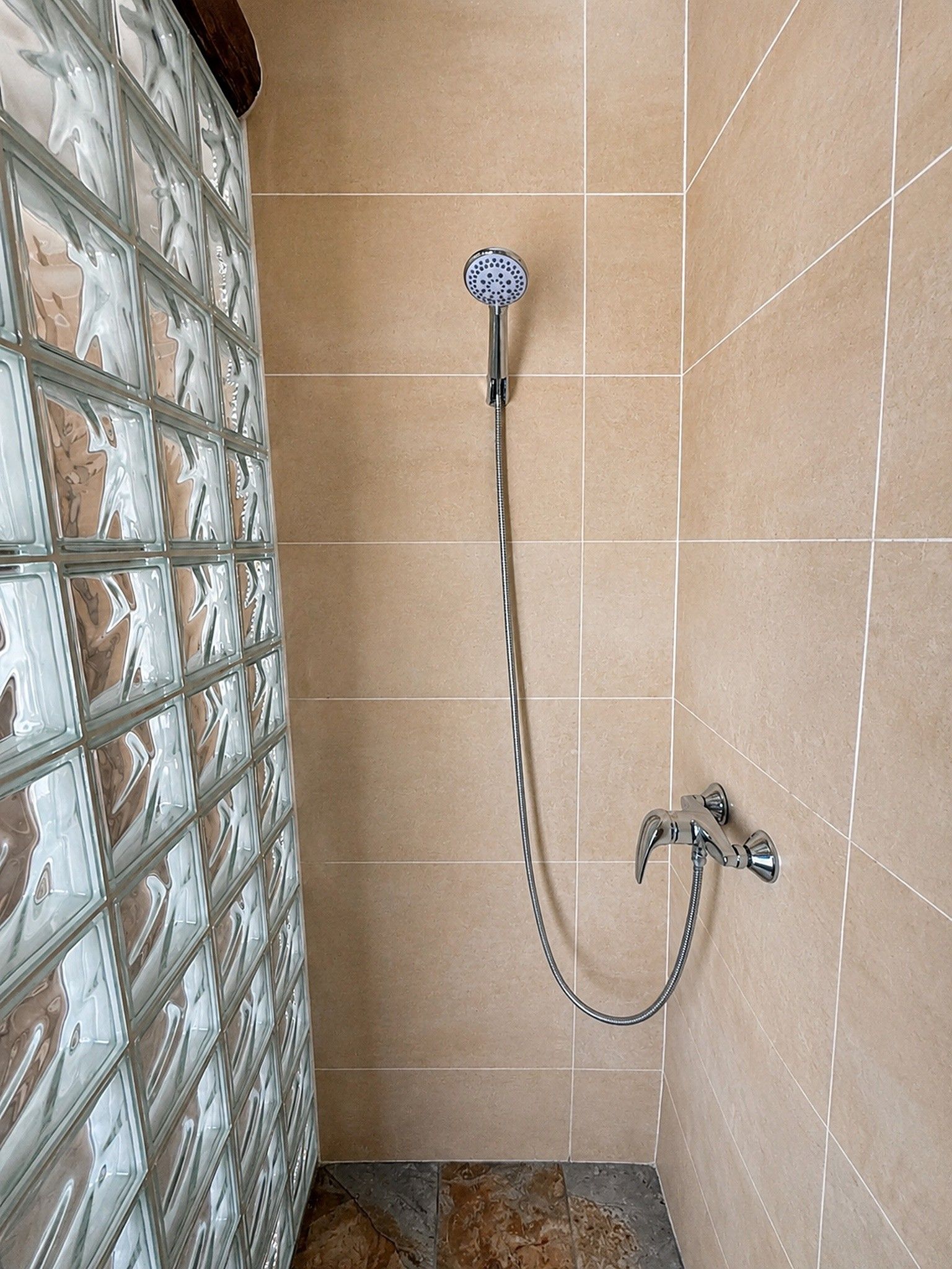 A shower area with a glass door and a handheld showerhead.