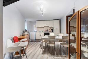 A modern kitchen with white cabinets, a dining table with chairs, and a red high chair.