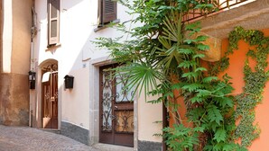 A cobblestone street, a building with a wrought iron gate, and a wall with climbing plants. - 'Casa Vacanza Malva' Apartment with Wi-Fi (Baveno)
