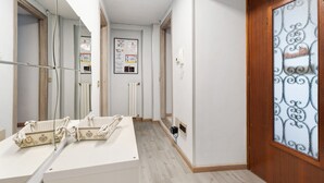 A hallway with a wooden door, a mirror, a bulletin board, and a white table with a checkered tablecloth. - 'Casa Vacanza Malva' Apartment with Wi-Fi (Baveno)