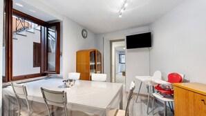 A modern dining area with a large table, chairs, a wooden cabinet, and a television mounted on the wall. - 'Casa Vacanza Malva' Apartment with Wi-Fi (Baveno)