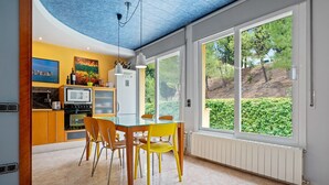 Et moderne køkken med spiseplads, store vinduer og udsigt til grønne områder.