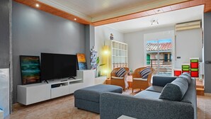 En moderne stue med et fladskærms-tv, grå sofaer, et hvidt tv-møbel og en bogreol.