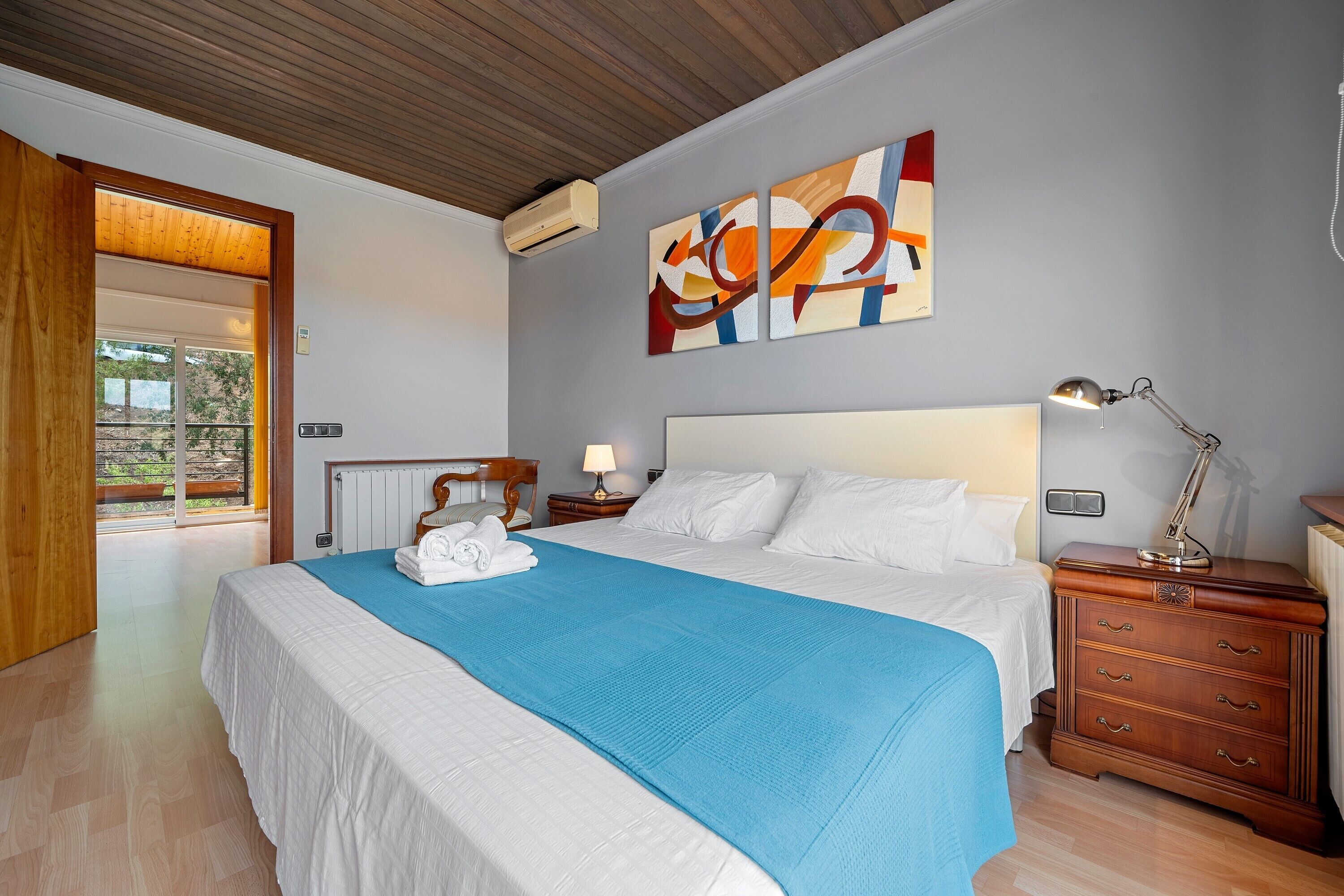 Une chambre à coucher avec un lit, une table de chevet, une lampe, une commode et un tableau au mur.