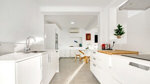 A modern kitchen with white cabinetry, a wooden countertop, and a central island. - Villa 'Ericito' with Private Pool, Wi-Fi and Air Conditioning (Dénia)