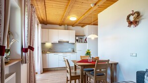 Una cucina accogliente con mobili in legno, un tavolo da pranzo con sedie e un sottopiattino rosso.