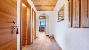 Un corridoio con pavimento in legno, una porta in legno e uno specchio al muro.