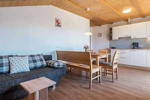 A modern living room with a sofa, a wooden table, and a dining area.