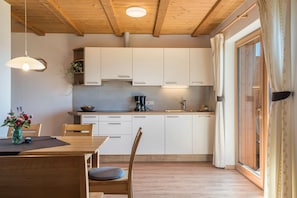 A modern kitchen with white cabinets, a wooden dining table, and a large window with curtains. - Holiday Apartment 'Mongaduierhof Apt Schlern' with Mountain View, Shared Garden & Wi-Fi (Fie' allo Sciliar)