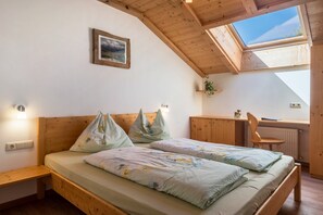 A bedroom with a skylight, wooden headboard, a desk, and a chair.