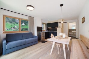 Un salon moderne avec un canapé, une table à manger et une cuisine en arrière-plan.