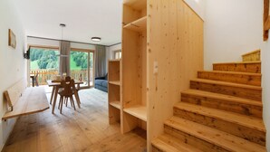 A wooden staircase, a dining area with a bench and chairs, and a view of the outdoors through large windows. - Apartment 'Herrischner 1' with Mountain View, Private Terrace and Wi-Fi (Moos in Passeier)