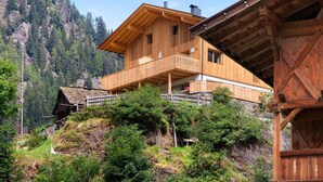 A wooden chalet with a balcony, set against a mountainous backdrop. - Apartment 'Herrischner 1' with Mountain View, Private Terrace and Wi-Fi (Moos in Passeier)