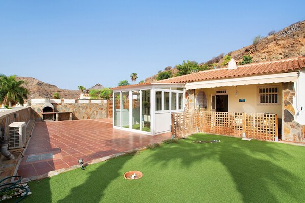 A residential property with a patio, artificial grass, a stone wall, and a view of the hills.