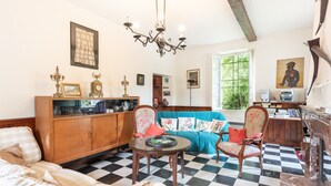 A room with a checkered floor, a sofa, a wooden cabinet, and a chandelier. - La serre, grande maison  dans un grand jardin. (Laborde)