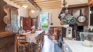 A rustic kitchen with wooden furniture, a dining table, and various kitchen utensils. - La serre, grande maison  dans un grand jardin. (Laborde)
